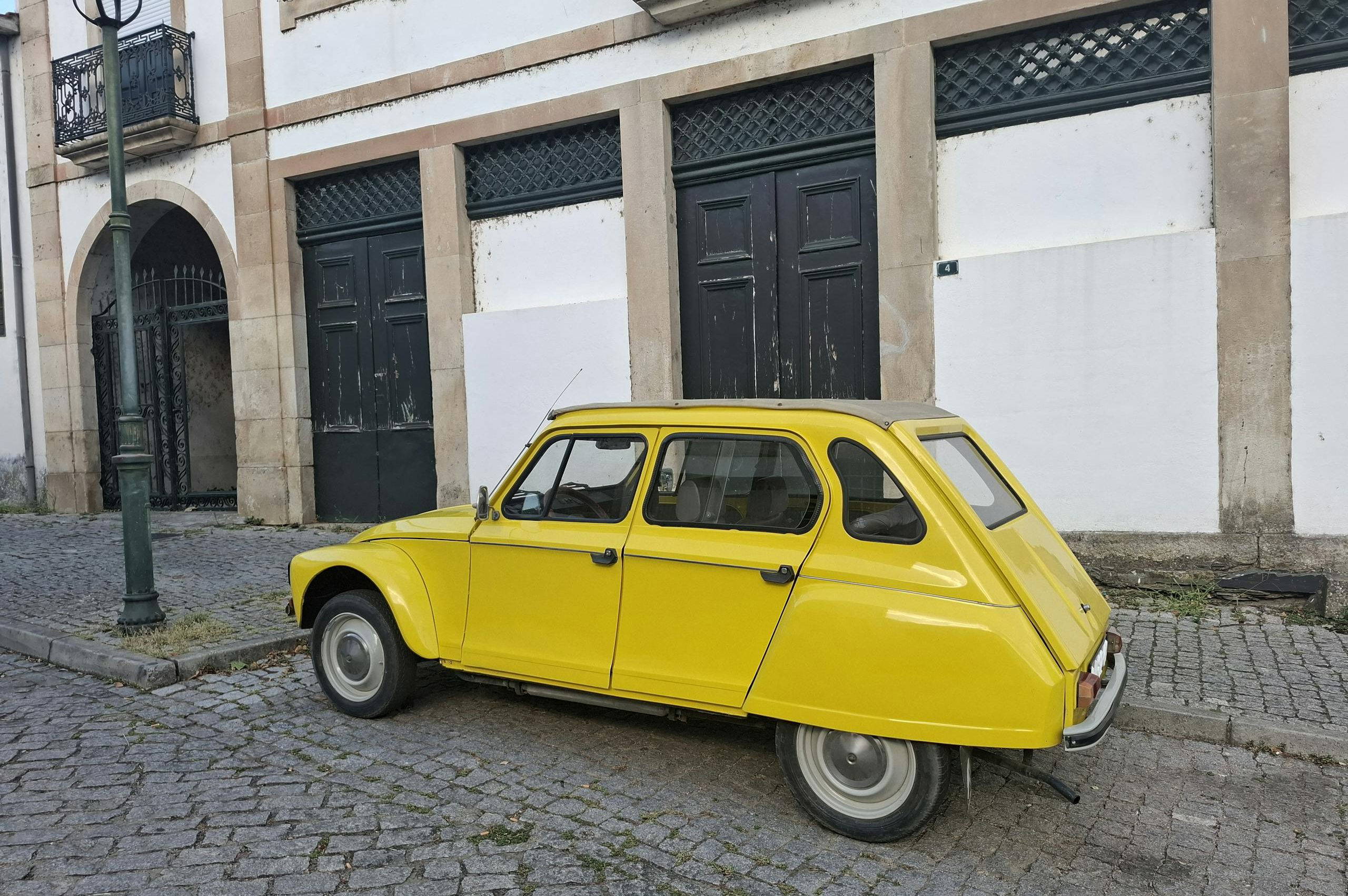 Classic yellow car parked on a cobblestone street against historic architecture
