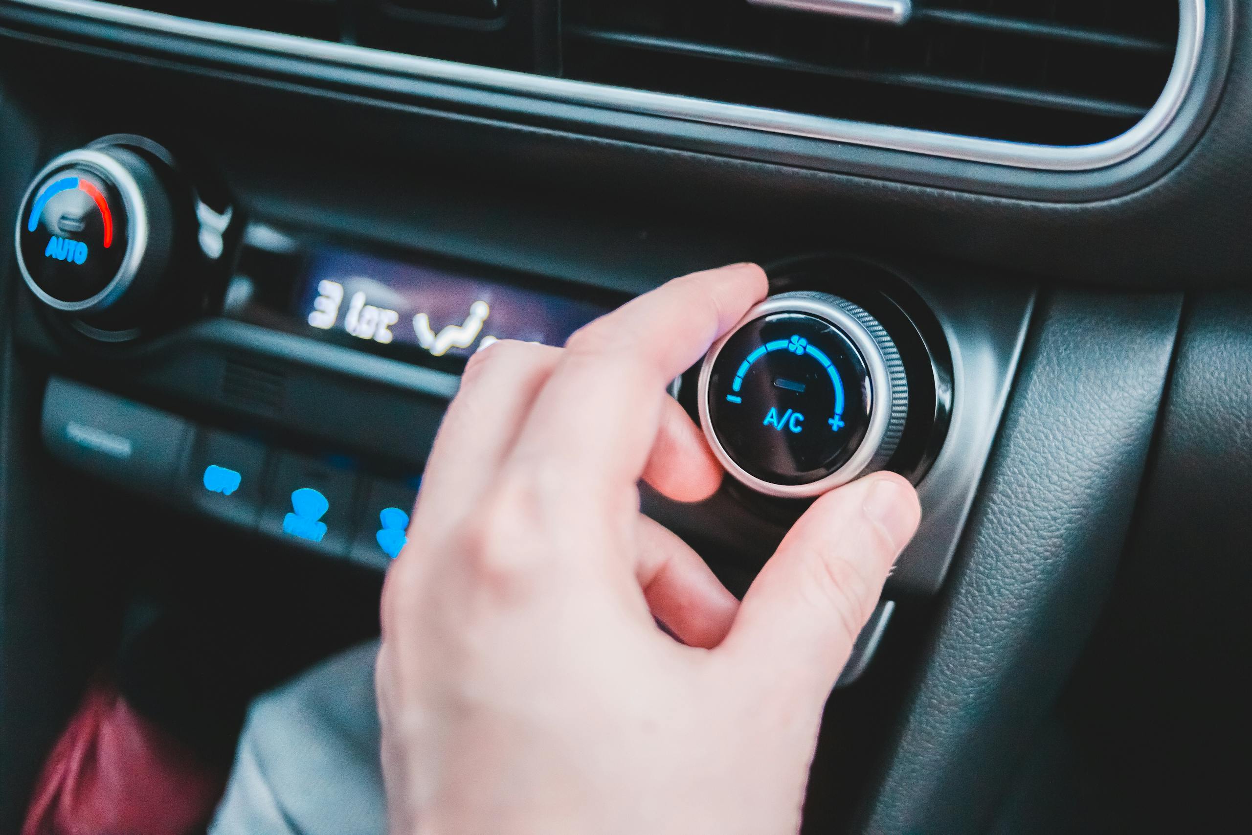 Crop anonymous person regulating temperature in car using controller on panel while sitting in car